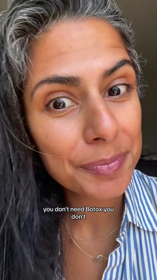 a woman with gray hair is wearing a striped shirt and a necklace .