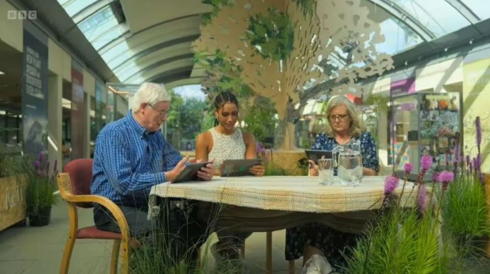 a group of people sitting at a table with a sign that says bbc on it