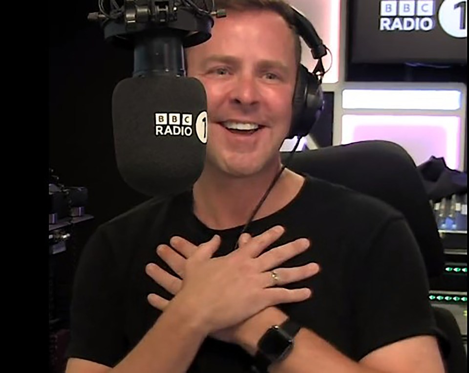 a man wearing headphones and a bbc radio 1 microphone