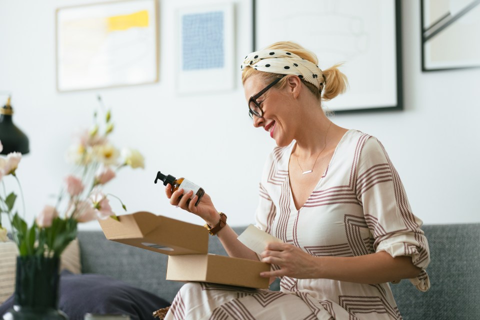 a woman sitting on a couch holding a bottle and a box