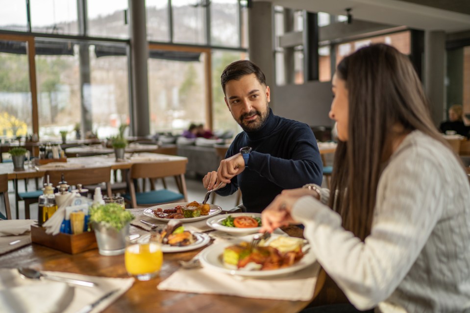 a man and a woman are sitting at a table eating food