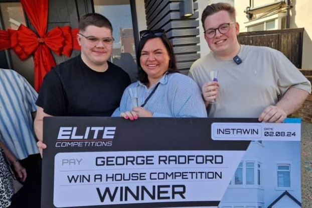 a group of people standing next to each other holding a large check .