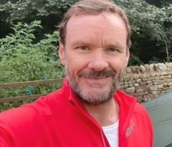 a man with a beard is taking a selfie in front of a tent .