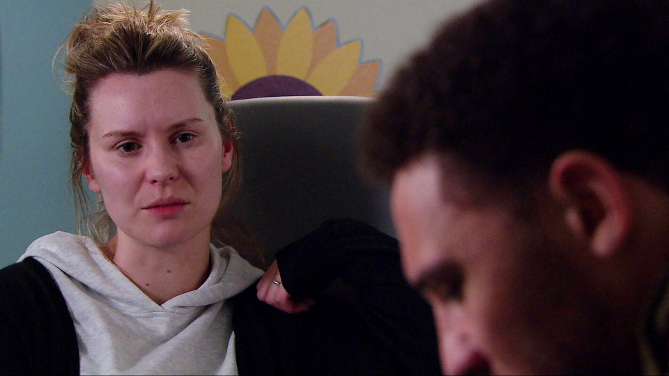 a man and a woman are sitting in a chair with a sunflower painted on the wall behind them