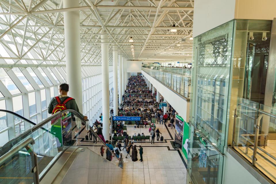 a man walking down an escalator in an airport with a sign that says arrivals and departures