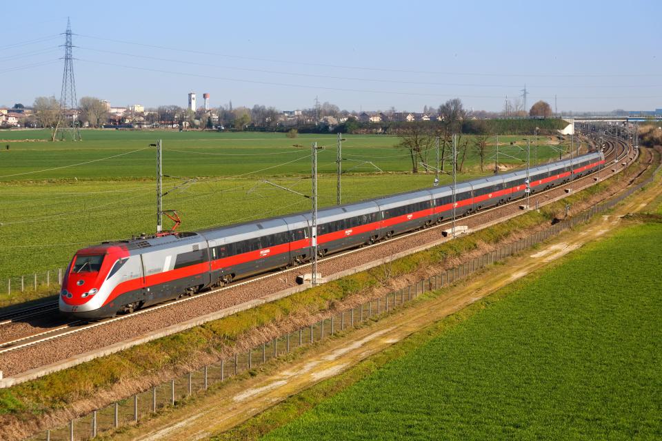 a red and gray train is going down the tracks