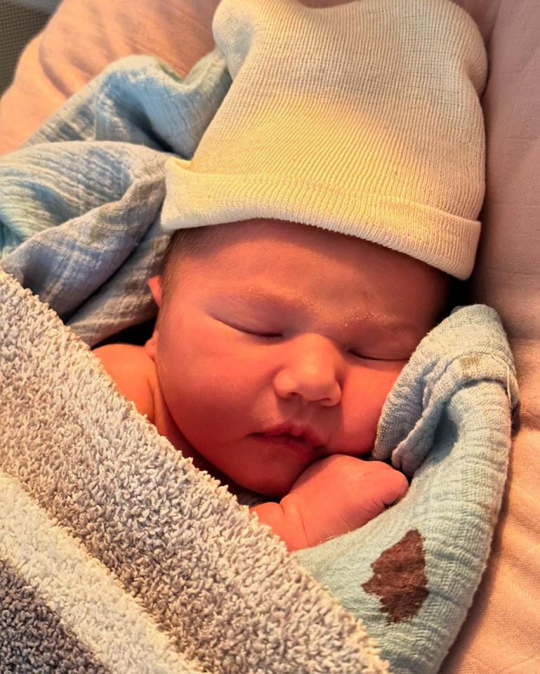 a newborn baby wearing a white hat is wrapped in a blue blanket