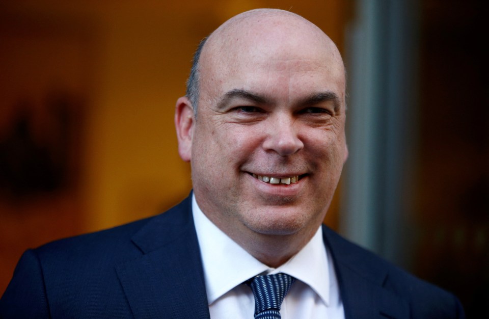 a bald man in a suit and tie smiles for the camera