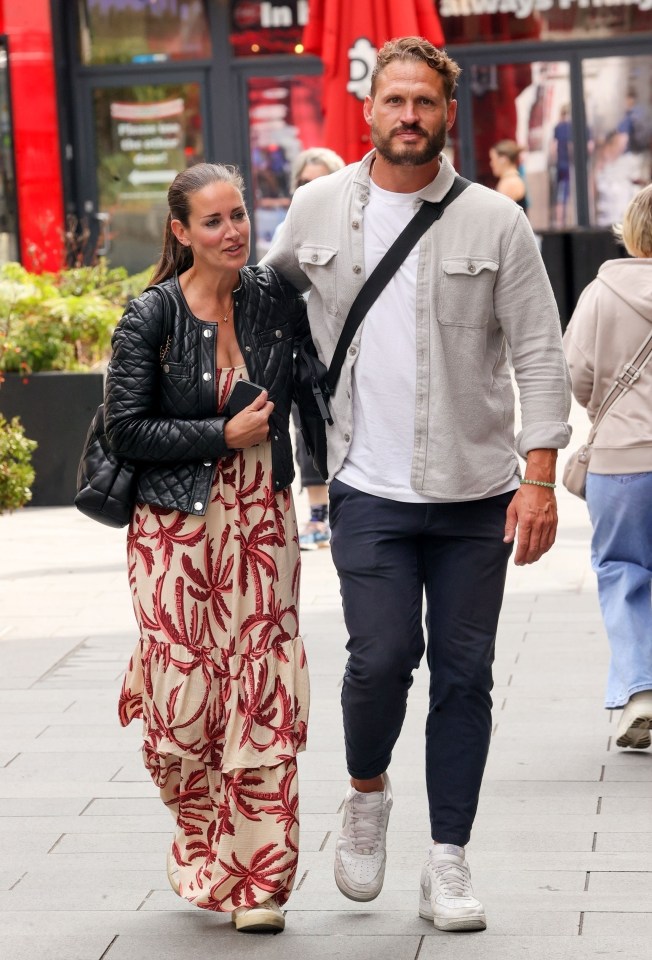 a man and a woman are walking down a sidewalk in front of a store that says ' in ' on it