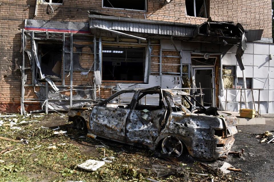 A burnt out car sits in front of an apartment building after a Ukrainian blast