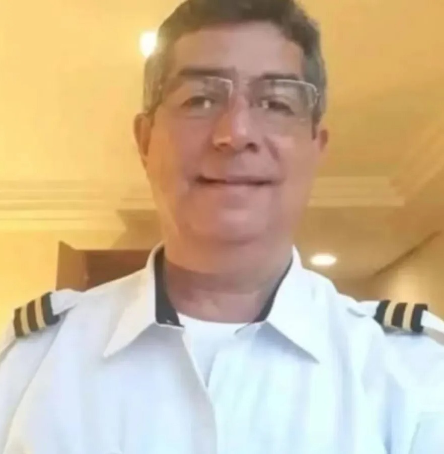 a man wearing glasses and a pilot 's uniform is smiling for the camera .