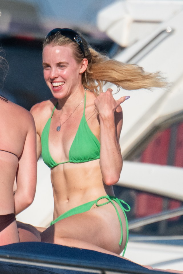 a woman in a green bikini is sitting on a boat