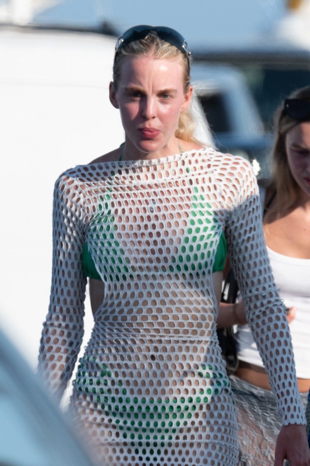 a woman wearing a white sweater and a green bikini top