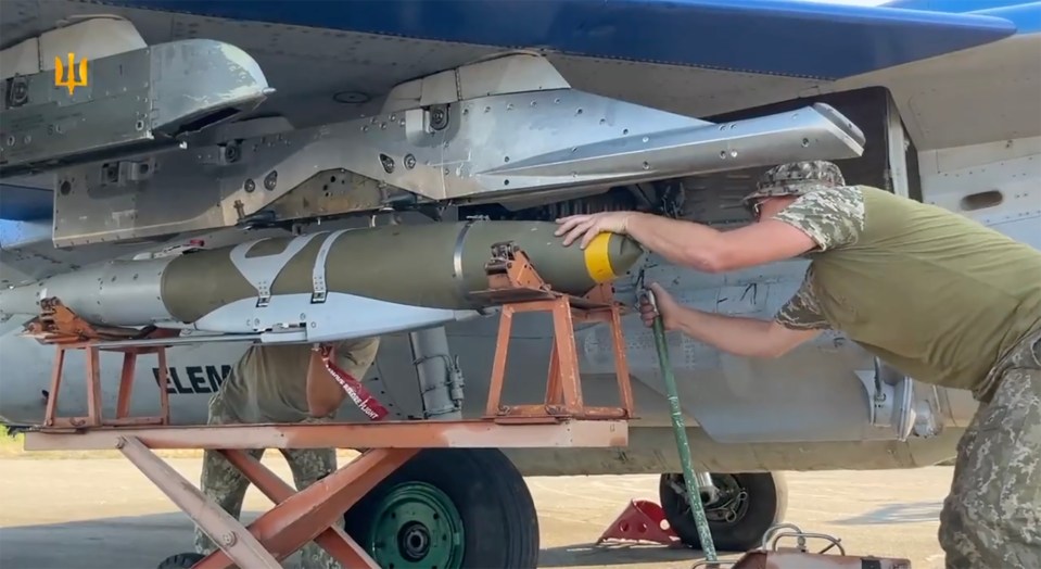 two soldiers are working on a military jet with a warning label that says " do not remove "