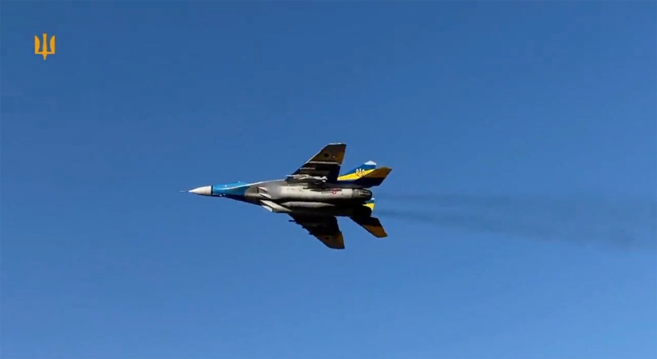 a blue and yellow fighter jet is flying through a blue sky