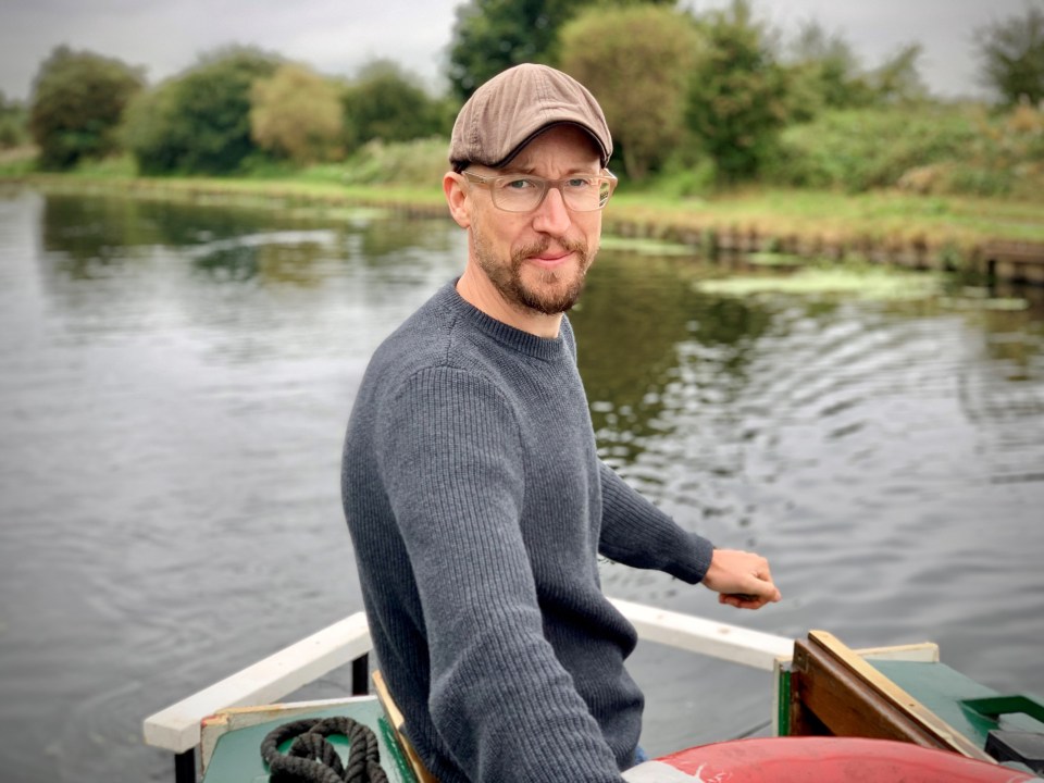 a man wearing glasses and a hat is sitting on a boat