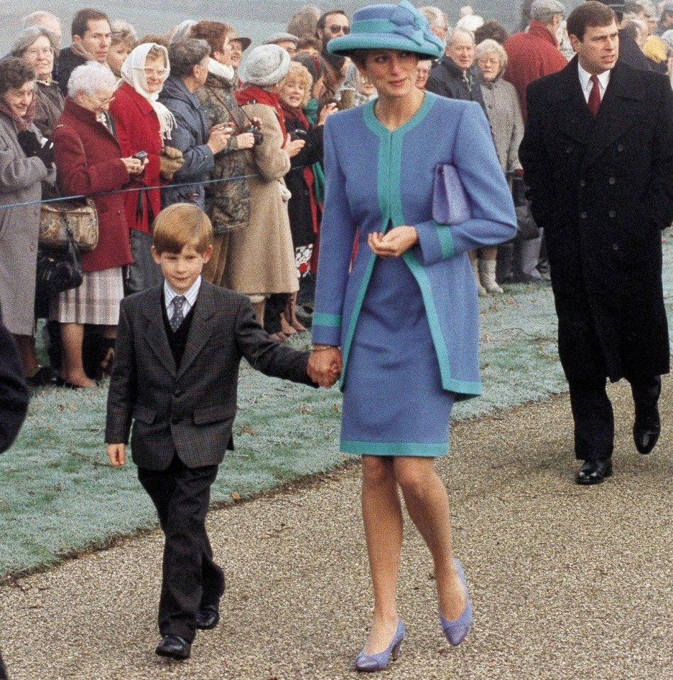 a woman in a blue coat is holding a boy 's hand