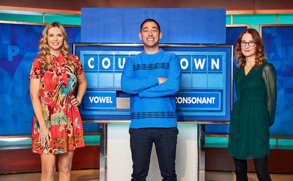 a man and two women stand in front of a board that says vowel and consonant