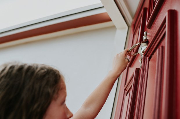 a little girl is knocking on a red door