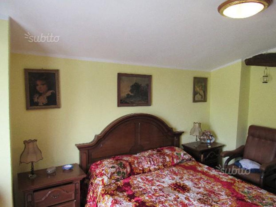 a bedroom with a bed and a chair with the word subito on the ceiling