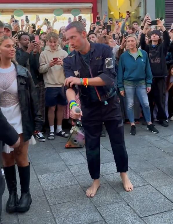 a man standing on a sidewalk with a crowd watching him