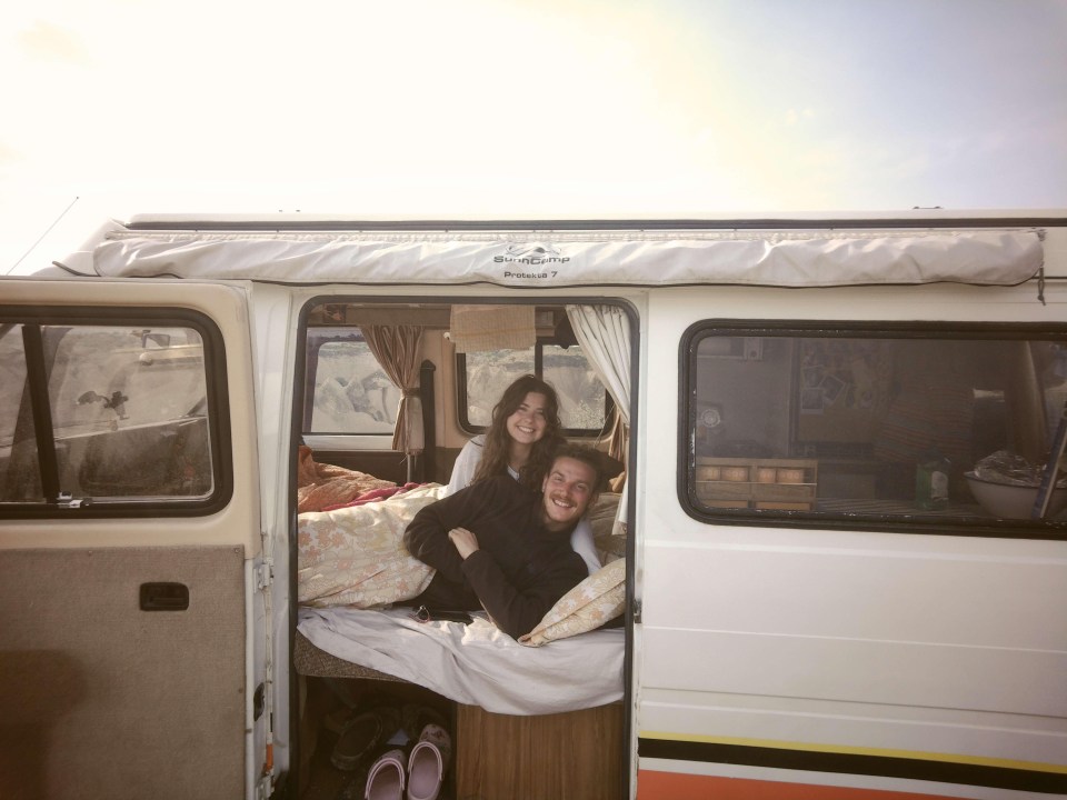 a man and a woman are laying in a camper van that says sherpa