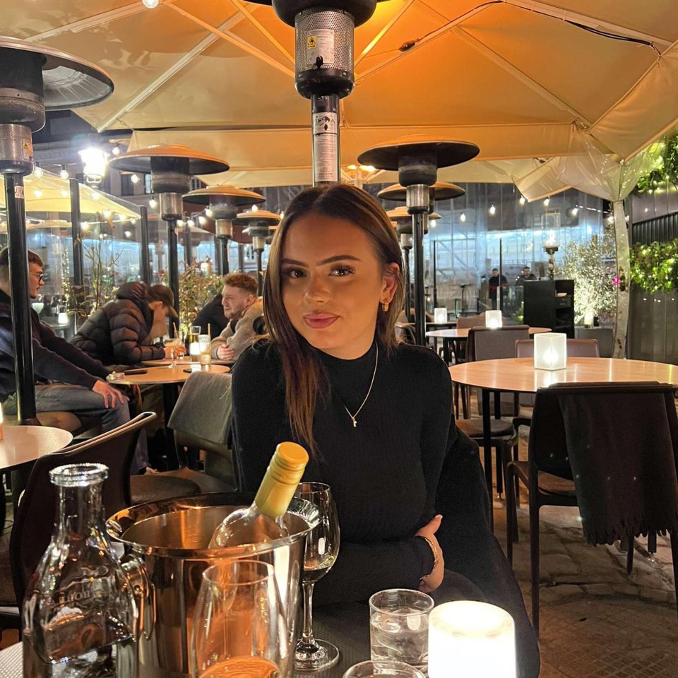 a woman sitting at a table with a bottle of wine