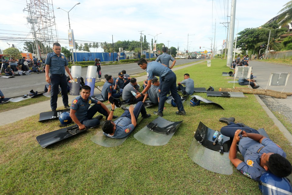 Anti-riot police rest outside the Kingdom of Jesus Christ compound after trying to find Quiboloy since Saturday