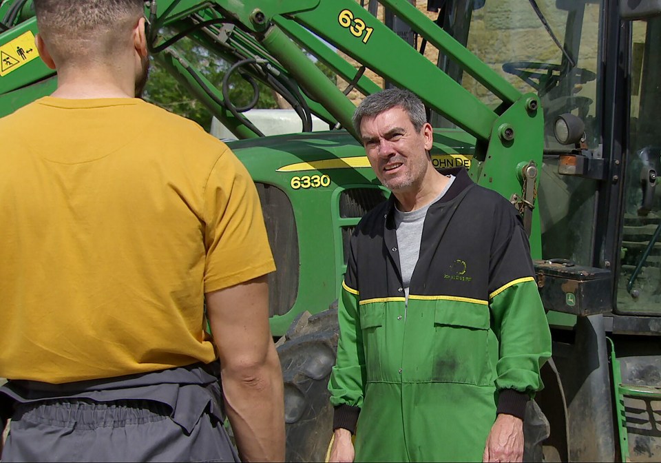 two men are standing in front of a green john deere tractor