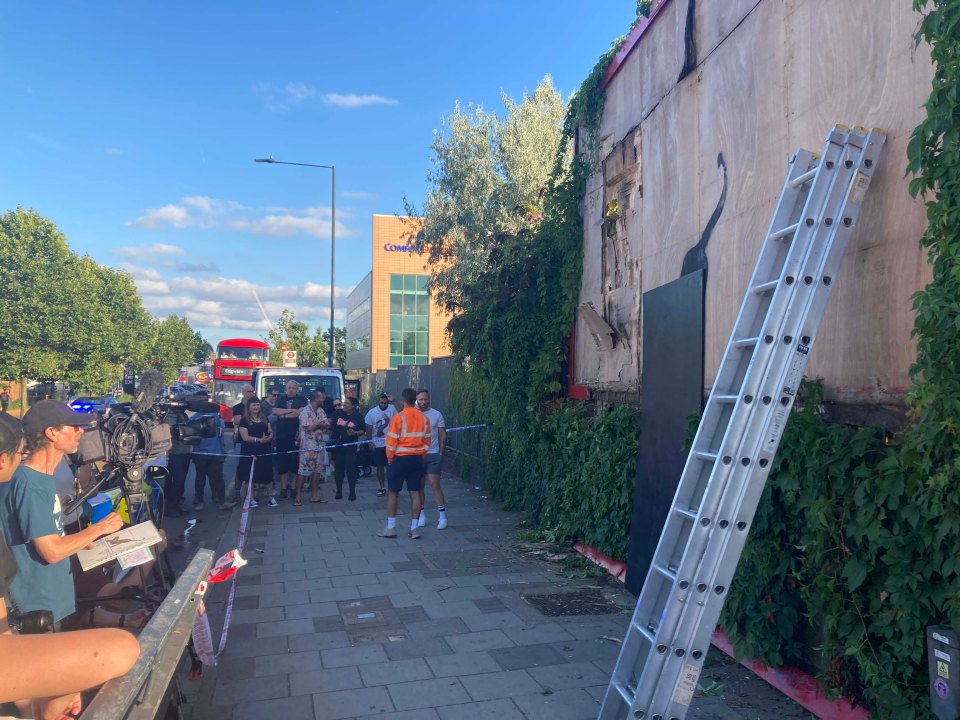 Onlookers booed as the workers covered the work in a board and then removed it