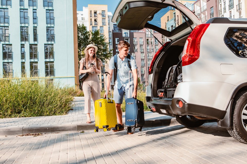 a man and a woman are pulling luggage out of the back of a car