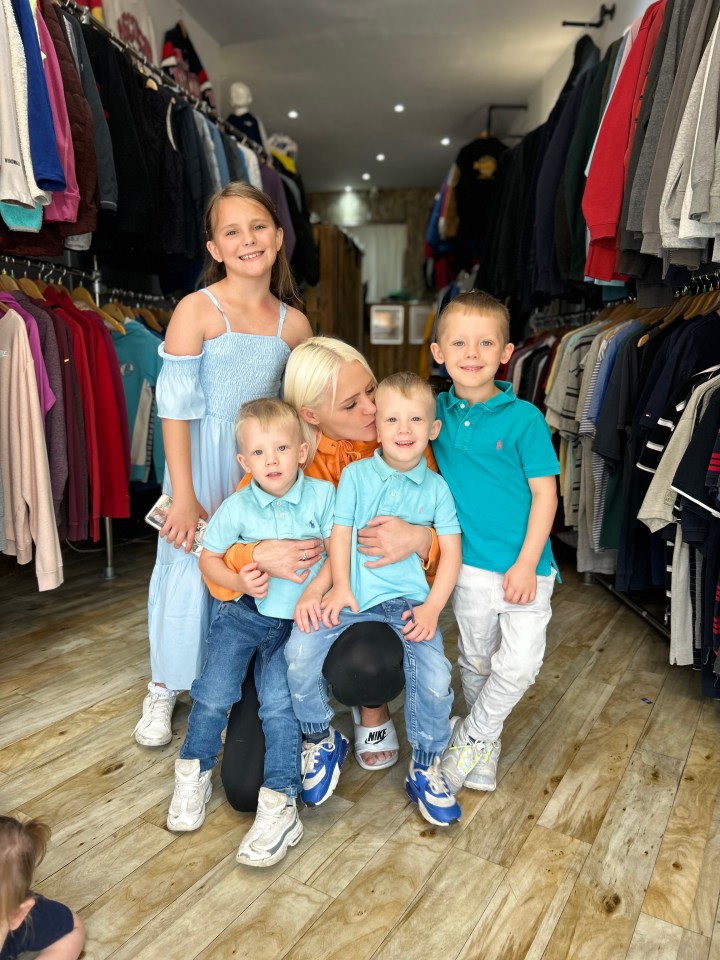 a woman and three children pose for a picture in a clothing store