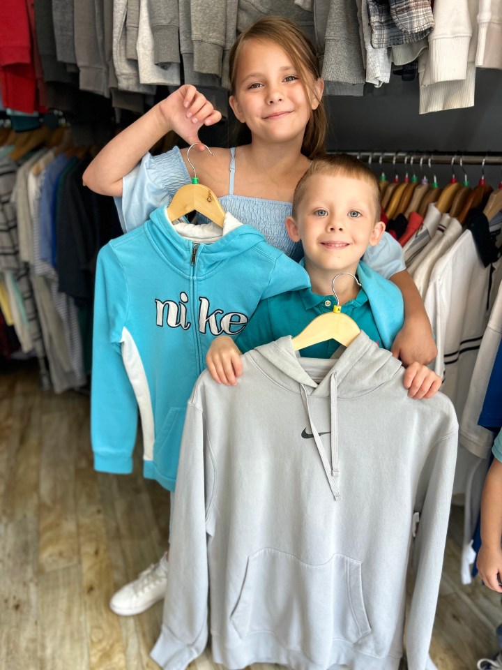 a boy and a girl are holding up nike sweatshirts