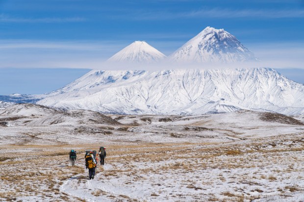 a group of people walking in the snow with mountains in the background