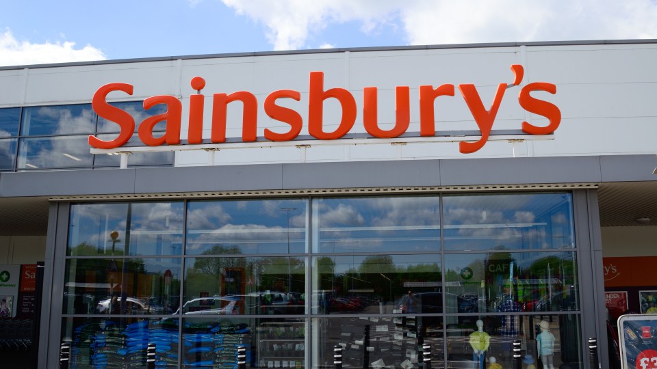 a sainsbury 's store with a large orange sign