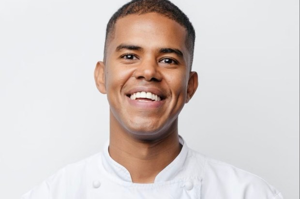 a man in a white chef 's coat smiles for the camera