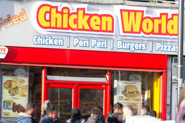 a group of people standing outside of a chicken world restaurant