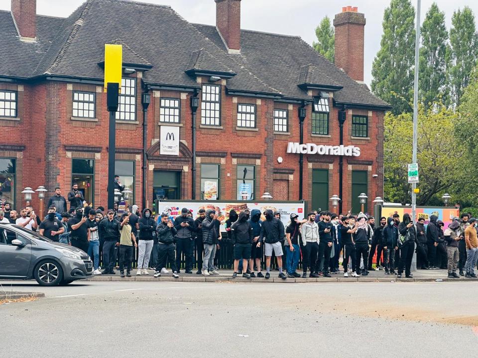 a group of people standing outside of a mcdonald 's