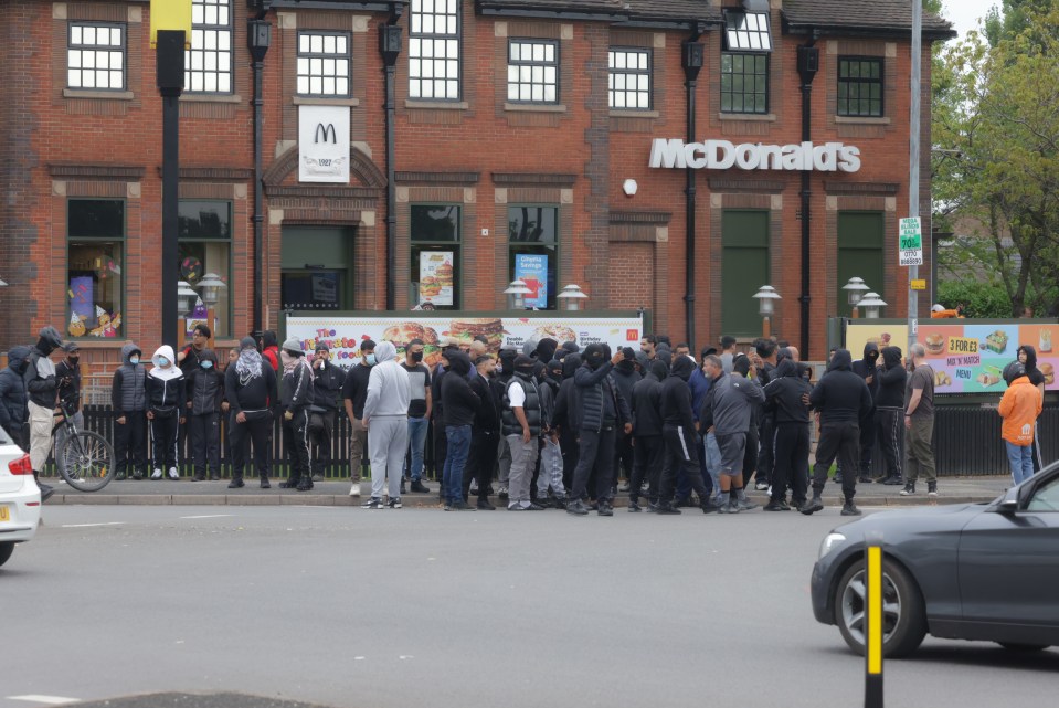 a group of people standing outside of a mcdonald 's