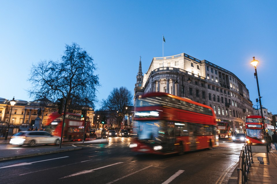 Red typical double decker bus blurred in Trafalgar Square.