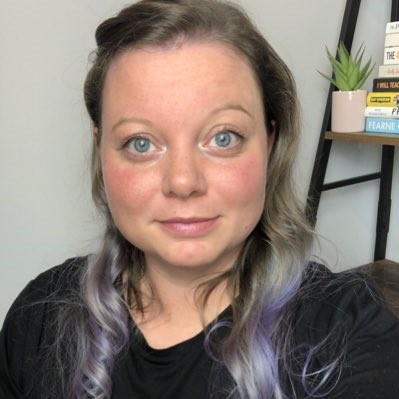 a woman with purple hair is taking a selfie in front of a bookshelf .