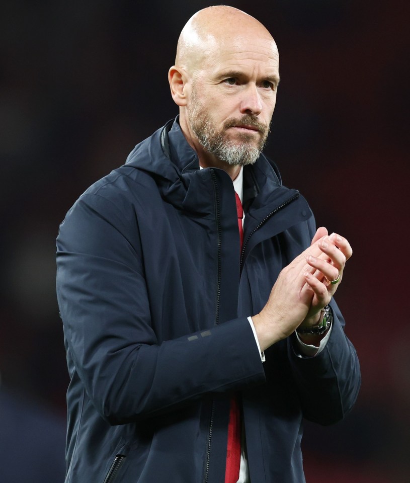 a bald man with a beard wears a blue jacket and a red tie