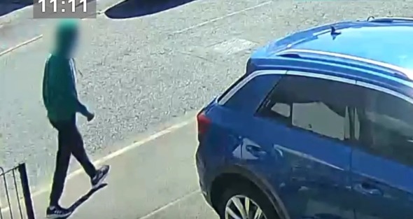 a man is walking next to a blue car in a parking lot .