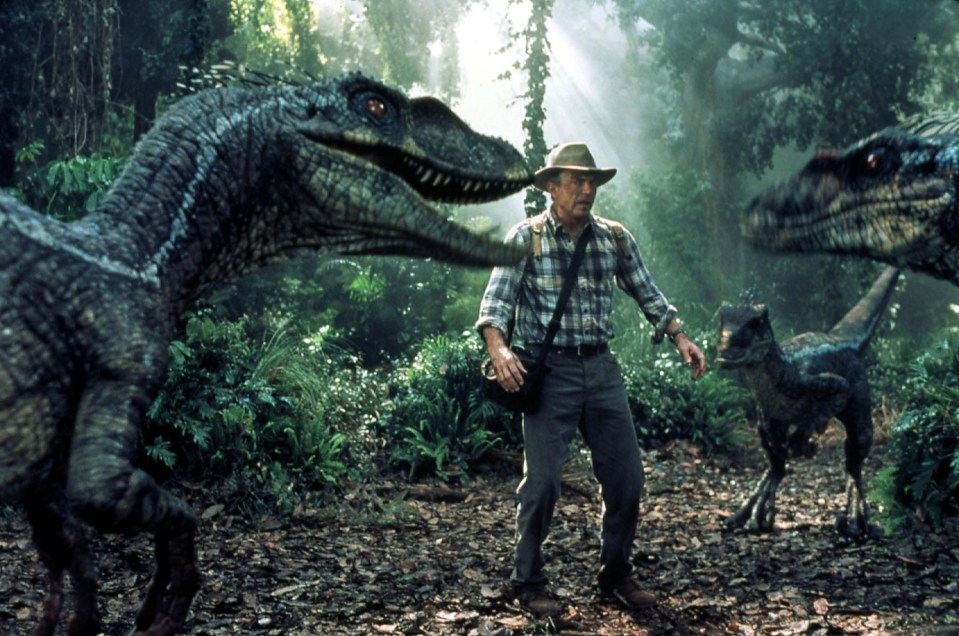 a man in a plaid shirt is surrounded by dinosaurs