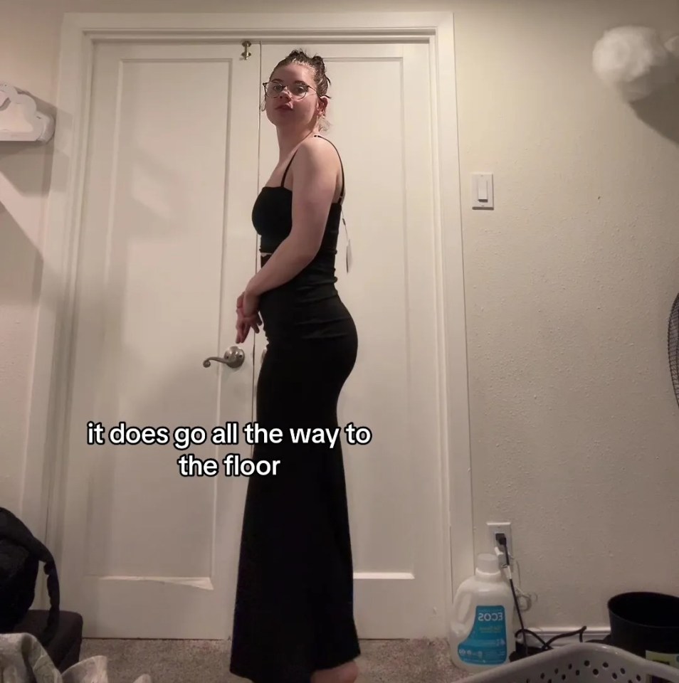 a woman in a black dress stands in front of a white door and says it does go all the way to the floor