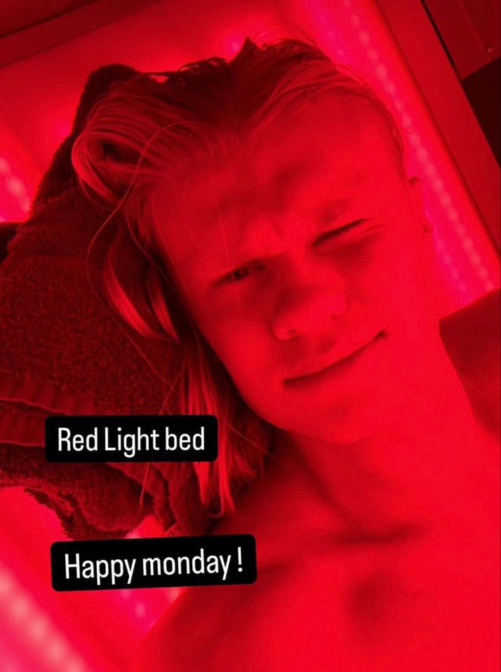 a phone screen shows a man laying in a red light bed