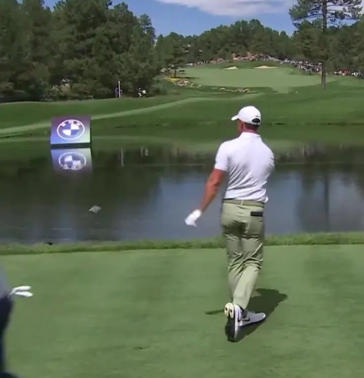 a man walking on a golf course with a bmw sign in the background