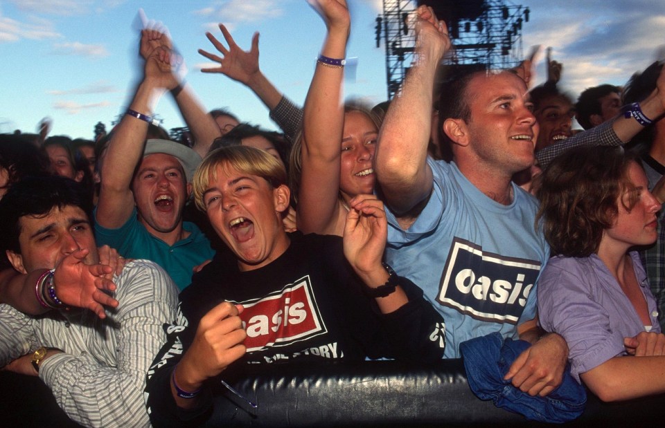 a group of people wearing oasis shirts are cheering