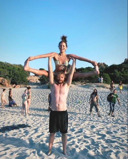 a man is carrying a woman on his shoulders on the beach