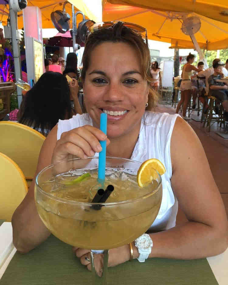 a woman drinking from a giant glass with a blue straw